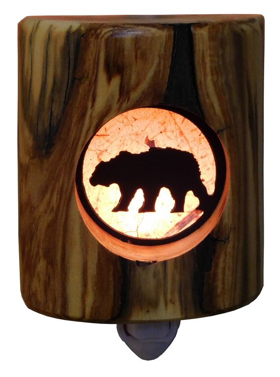 A wooden log night light with an silhouette of a bear cut into the wood, illuminated from within.